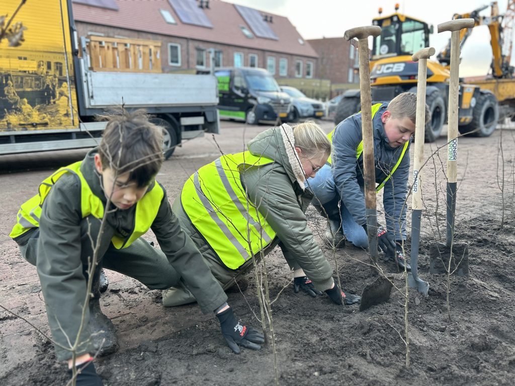 Kinderen planten bomen en een haagbeuk tijdens Boomfeestdag 2025.