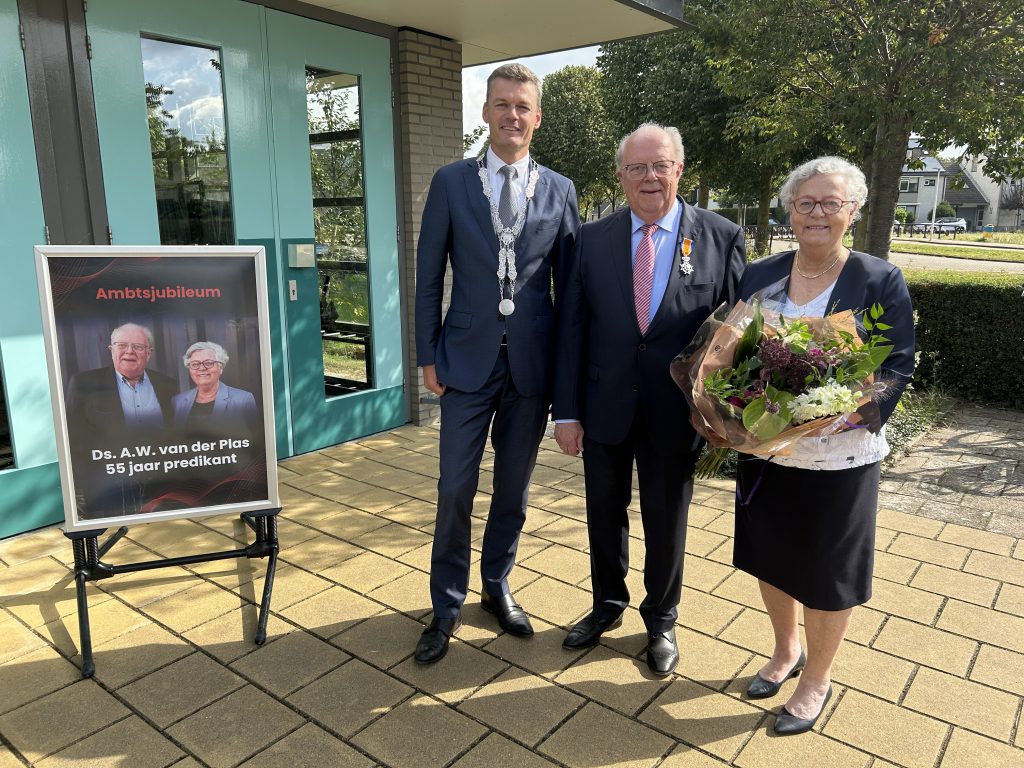 Burgemeester Nieuwenhuis en de heer en mevrouw Van der Plas met een bos bloemen