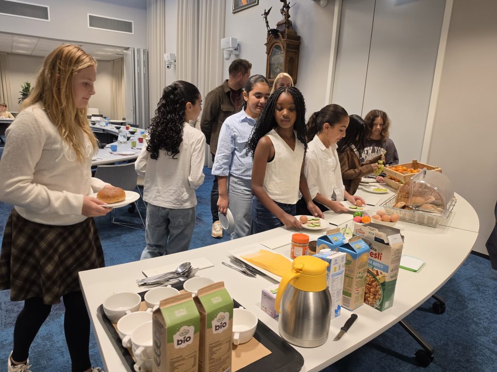 Kinderen staan aan het ontbijtbuffet in de raadzaal van het gemeentehuis.